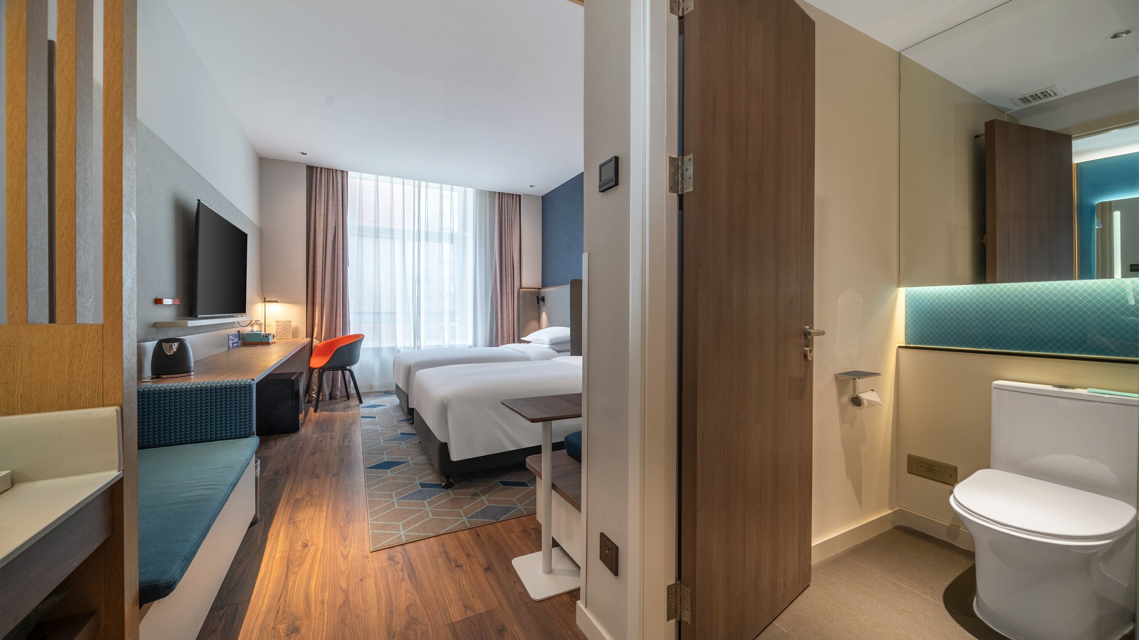 A hotel room with a bed, desk, chair, and a bathroom.