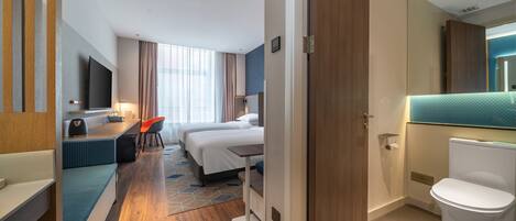 A hotel room with a bed, desk, chair, and a bathroom.