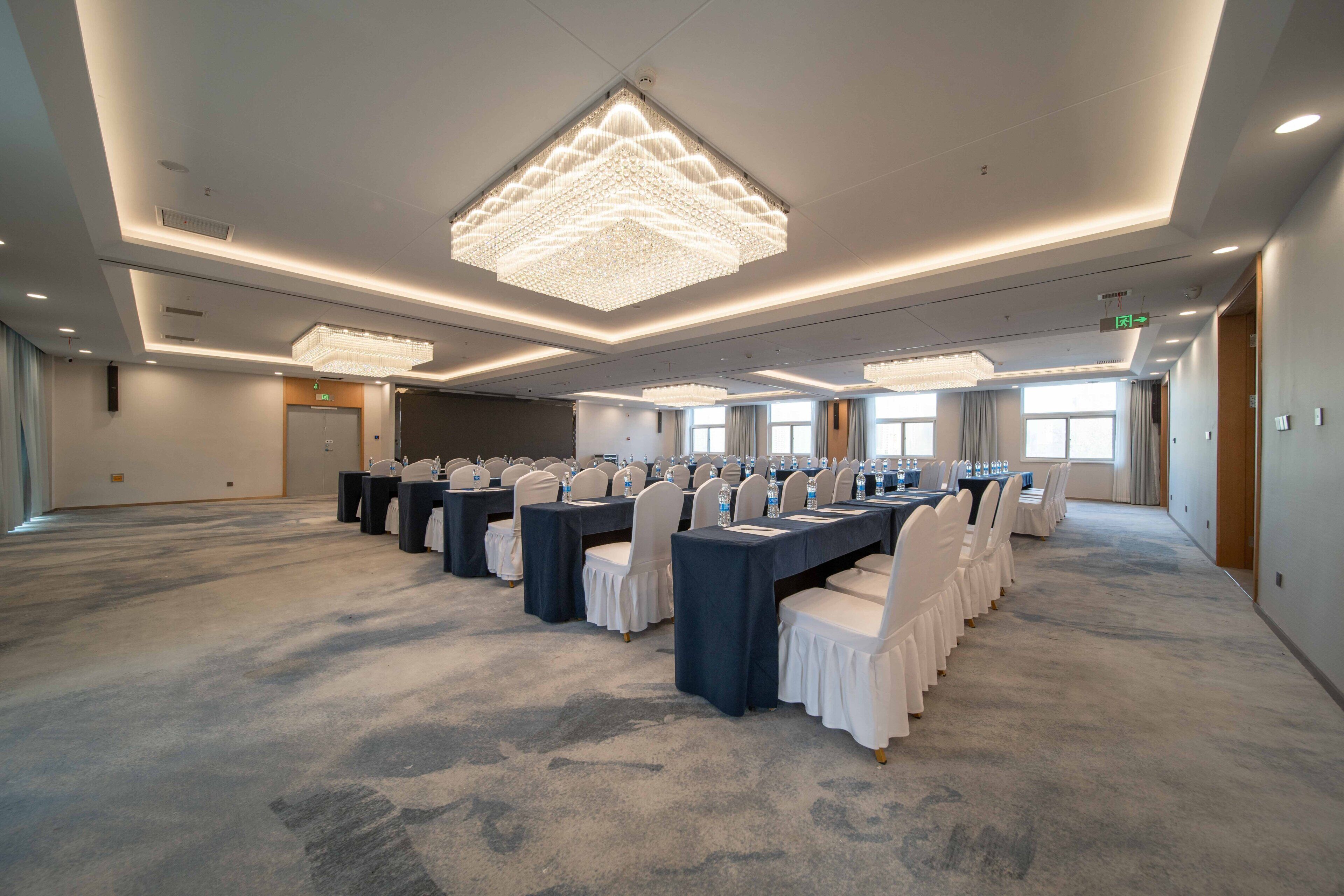 Un salón de conferencias con varias mesas, sillas y una gran lámpara de araña.