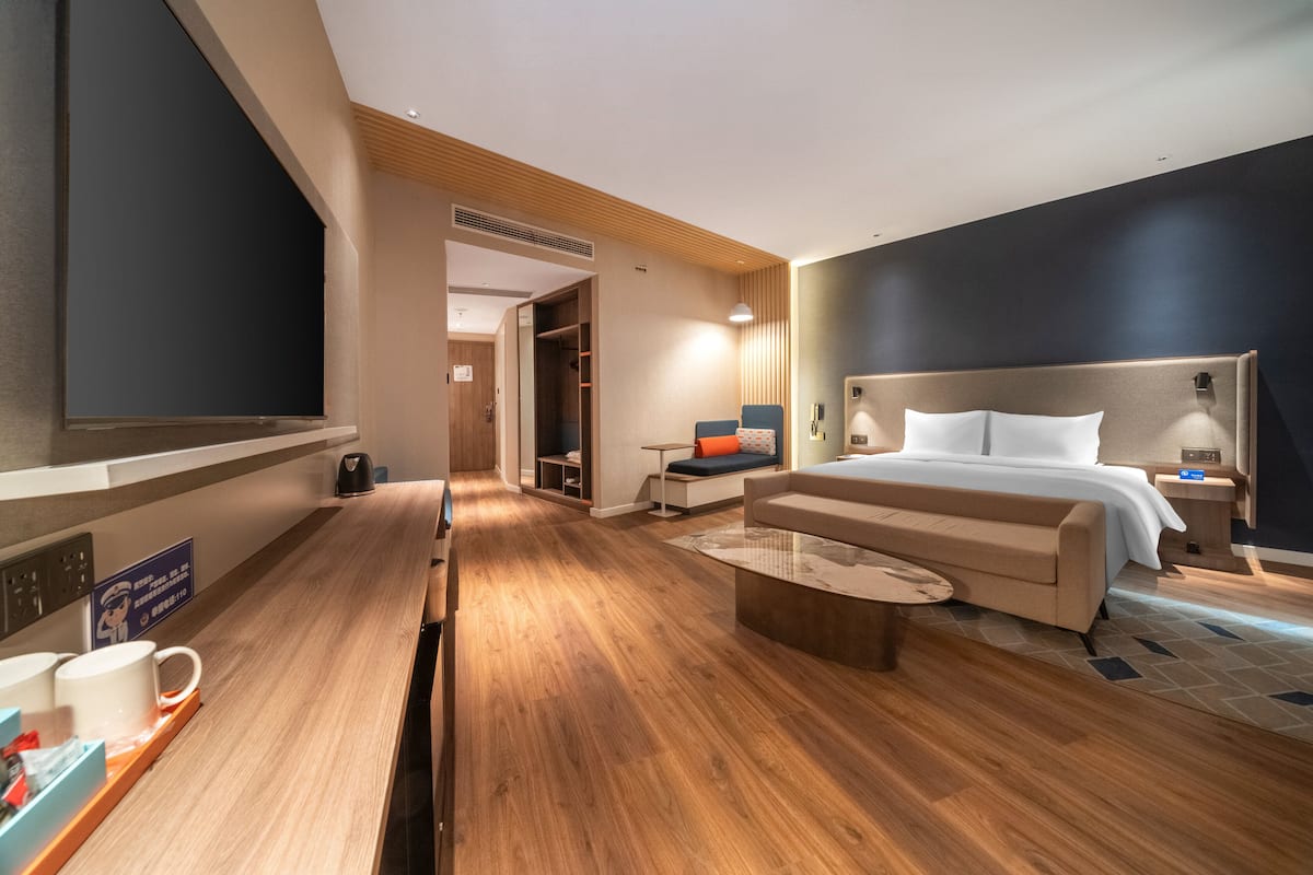 Ein modernes Hotelzimmer mit einem großen Bett, einer Couch, einem Couchtisch und einem Fernseher.