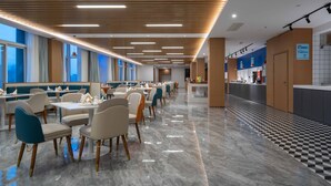 Un restaurante moderno con una barra larga, varias zonas de estar y un suelo con estampado de cuadros.
