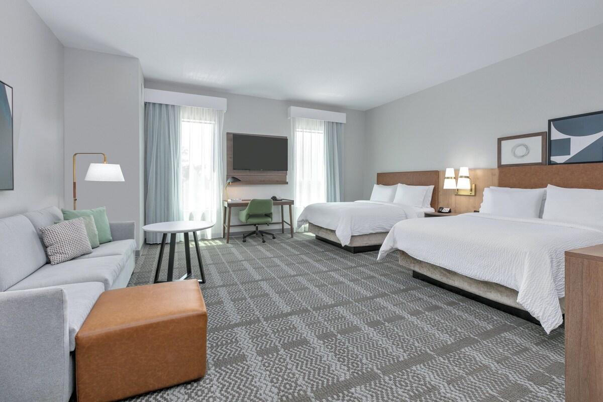 A hotel room with a bed, a sofa, a desk, and a television.