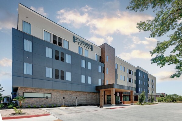 A Staybridge Suites hotel with a modern architectural design, featuring a mix of glass and wood facade, and a spacious entrance area. - Staybridge Suites San Antonio Lackland AFB Area by IHG (San Antonio)
