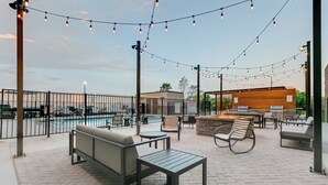 An outdoor patio area with seating, a pool, and string lights. - Staybridge Suites San Antonio Lackland AFB Area by IHG (San Antonio)