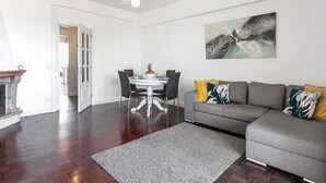 Un salon moderne avec un canapé gris, une table à manger avec des chaises et une cheminée.