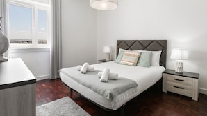 Une chambre d’hôtel moderne avec un grand lit, des tables de chevet, une fenêtre avec des rideaux et une vue sur la ville.