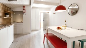 A modern kitchen with white cabinetry, a wooden countertop, and a red bench. - Ana's House - inside Óbidos Castle (Óbidos)