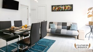A modern living room with a dining area, a sofa, and a TV. - Beach Alley Apartment (Nazaré)