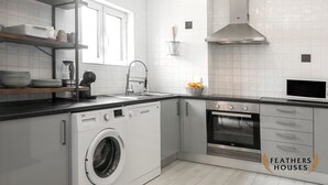 A modern kitchen with a built-in washer, oven, and microwave. - Beach Alley Apartment (Nazaré)
