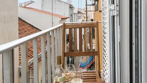 A balcony with a bottle of wine and two glasses, overlooking a cityscape with terracotta roofs. - Beach Alley Apartment (Nazaré)