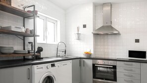 A modern kitchen with a built-in washer, oven, and microwave. - Beach Alley Apartment (Nazaré)
