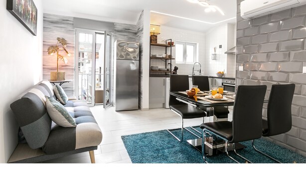A modern kitchen with a dining area, a sofa, and a view of the city. - Beach Alley Apartment (Nazaré)
