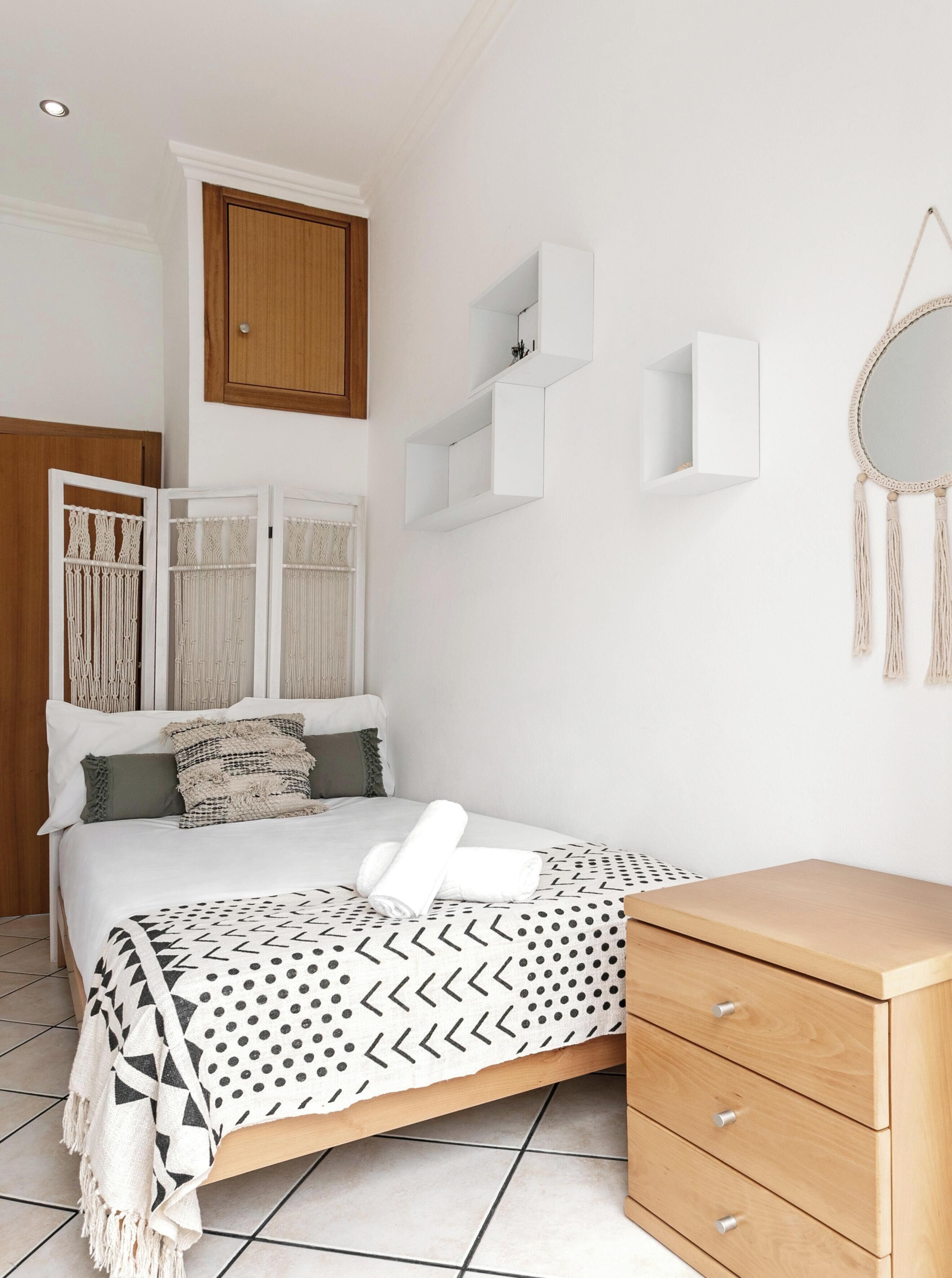 A bedroom with a bed, a wooden dresser, and a wardrobe.