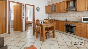 Una cocina con armarios de madera, una mesa de comedor con sillas y un microondas.
