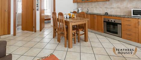 Una cocina con armarios de madera, una mesa de comedor con sillas y un microondas.