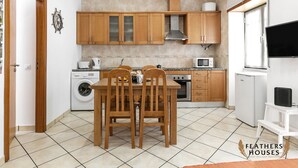 Una cocina compacta con armarios de madera, horno empotrado, microondas y lavadora.