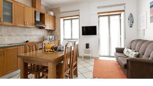 Una cocina moderna con armarios de madera, una mesa de comedor con sillas, un televisor de pantalla plana y un sofá en la sala de estar.
