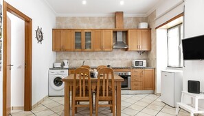 A compact kitchen with wooden cabinets, a built-in oven, a microwave, and a washing machine.