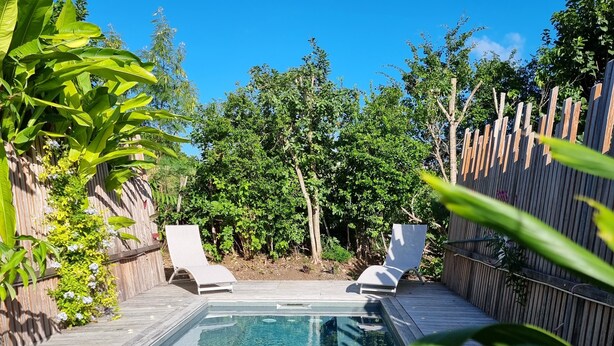 Un patio trasero con piscina, dos sillas de descanso y una terraza de madera.