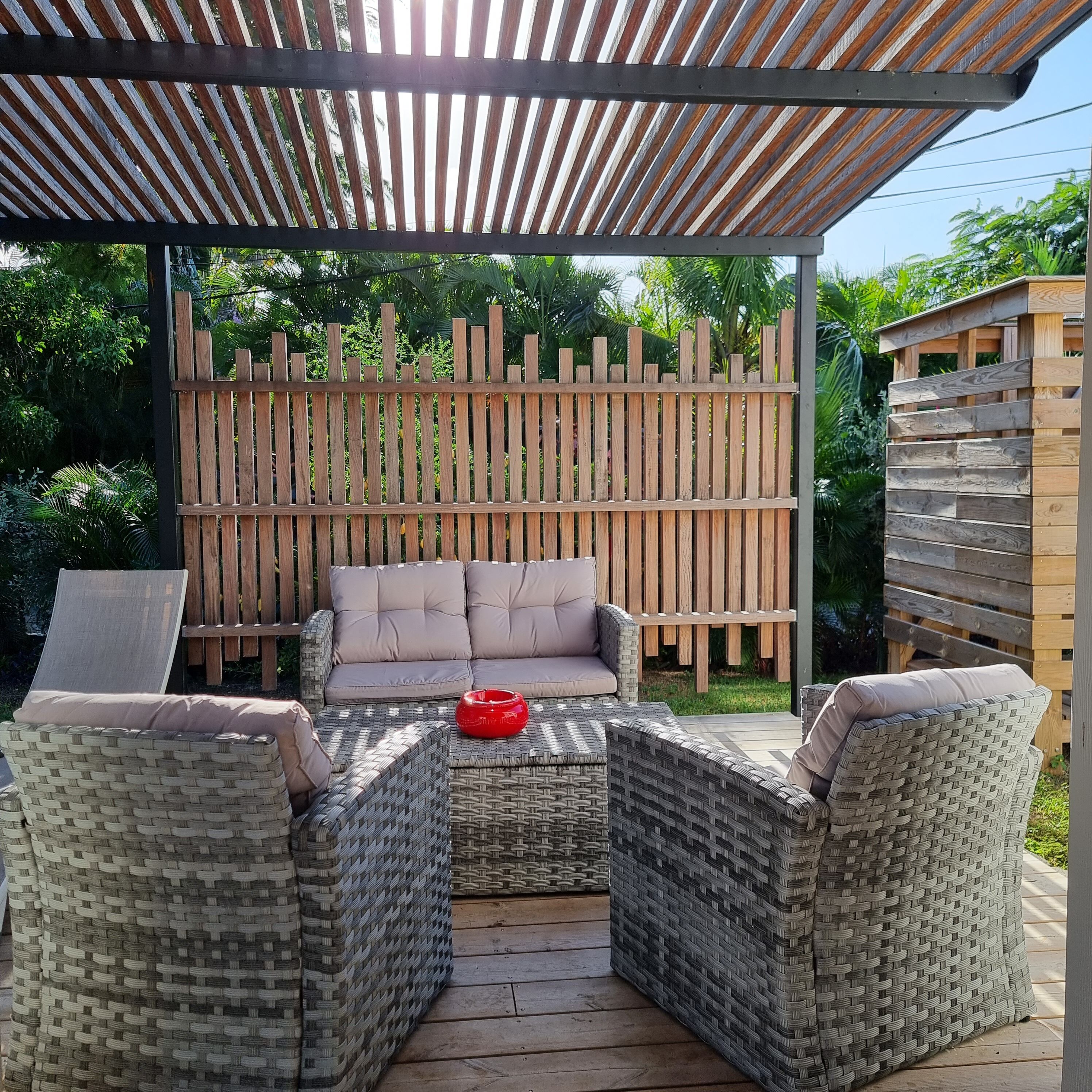A covered outdoor seating area with wicker furniture and a cushioned sofa.