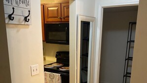 A kitchen with wooden cabinets, a microwave, and a stove. There is a sign on the wall that says "our home" with two hooks. - Cozy apartment steps from Christ Hospital, UC and minutes to downtown! (Cincinnati)