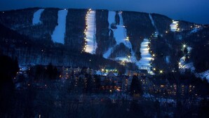 Une station de montagne au crépuscule, avec des bâtiments illuminés et un paysage enneigé.