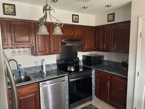 Kitchen area with double sink, stove, refrigerator, and microwave.