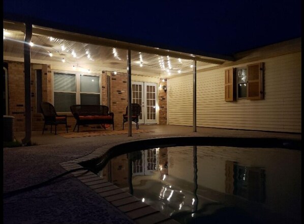 Relax by the pool in a serene outdoor space with a table and chairs.