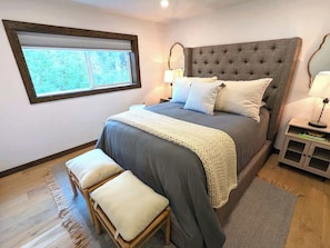 A bedroom with a large bed, a nightstand, a window, and a view of greenery outside. - New West Glacier Gem! RV's Welcome! Secluded! (West Glacier)