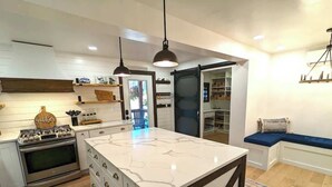 Una cocina moderna con una isla central, electrodomésticos integrados e iluminación colgante.
