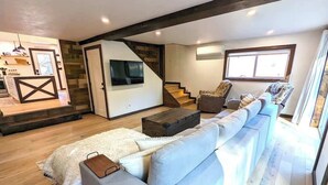 Una sala moderna con un sofá seccional, una mesa de centro y una escalera que sube a un nivel superior.
