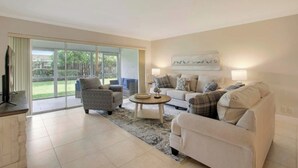 A spacious living room with a sofa set, a coffee table, and a TV on a stand. - 1 Block to the BEACH! King Beds! BBQ! (West Palm Beach)