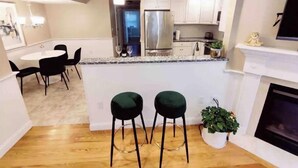 A modern kitchen with a central island, stainless steel appliances, and a dining area with black chairs. - Peaceful 2BR near US Route 1 and Boston. (Melrose)