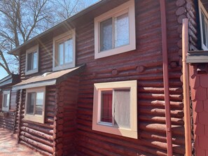 A log cabin with two visible windows and a chimney.