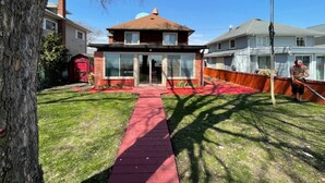 A residential property with a red pathway leading to a house with a brick facade and large windows. - Restored historic log cabin and deck on Lake Erie (Luna Pier)
