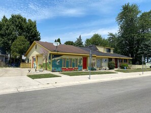 A two-story building with a satellite dish, a mural on the side, and a red door. - Restored historic log cabin and deck on Lake Erie (Luna Pier)