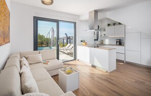 A modern living room with a sofa and coffee table, a kitchen with white cabinets, and a view of a swimming pool and lounge chairs. - Ferienhaus - Porec-Radmani (Radmani)