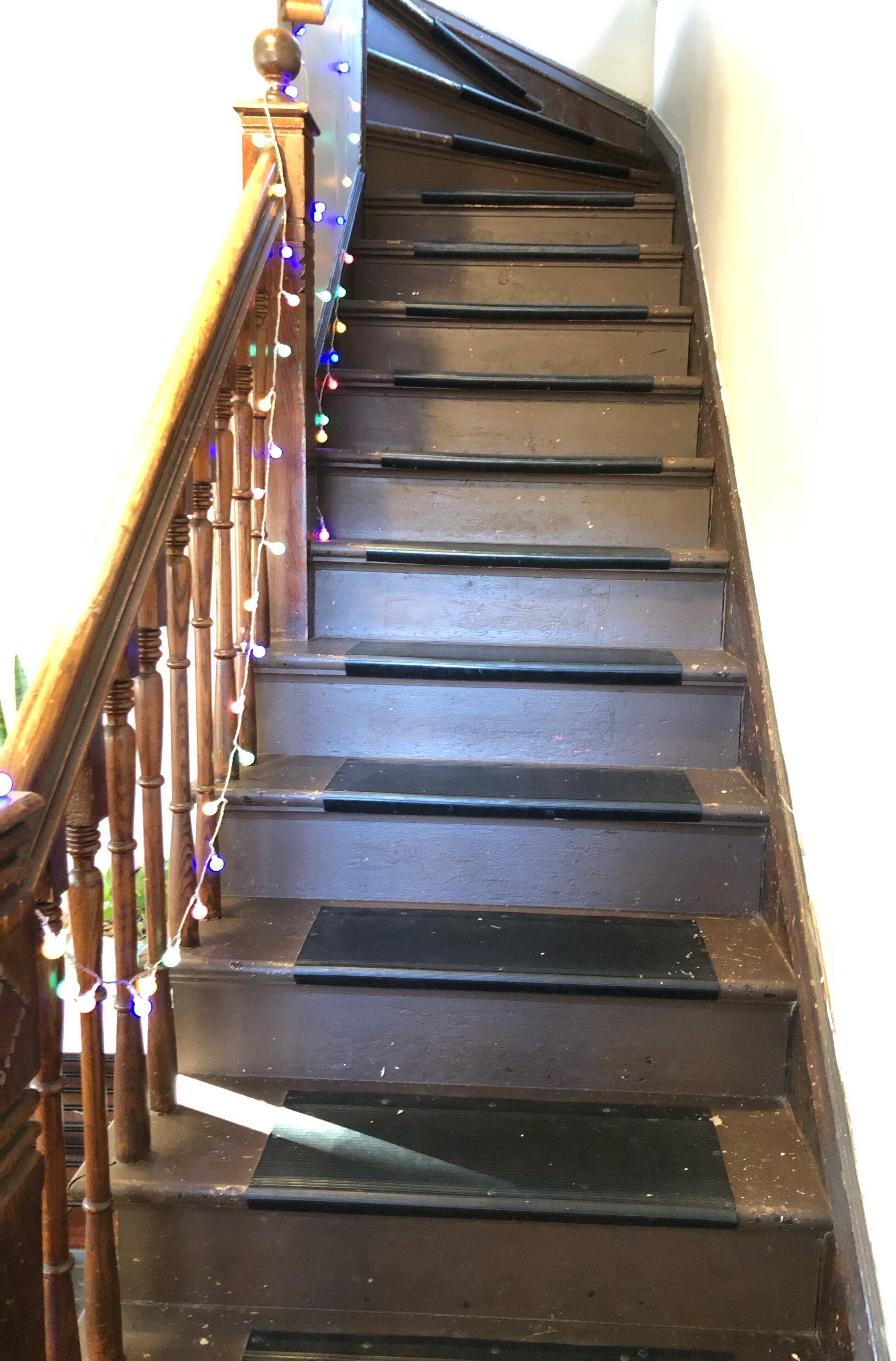 A wooden staircase with a handrail and string lights.