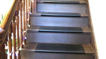 A wooden staircase with a handrail and string lights.