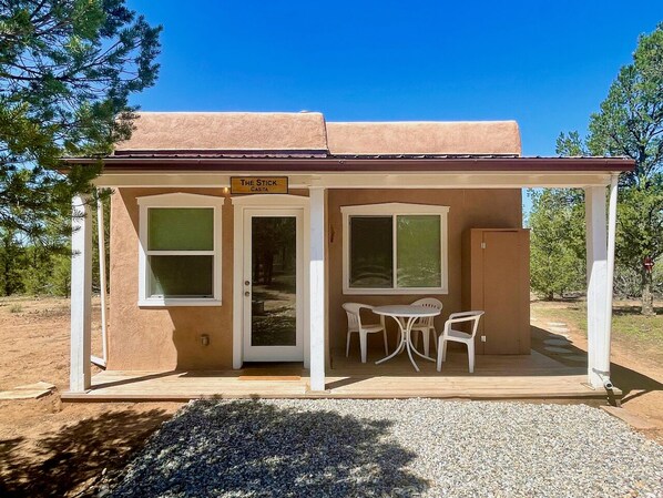 A small, single-story building with a covered patio area, a door, and two windows. - Escape to the Extraordinary in NM! (Carson)