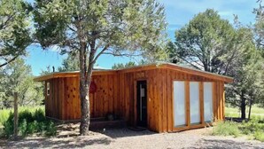 A wooden cabin with a single door and windows, surrounded by trees and gravel. - Ranch House Respite outside Taos, New Mexico! (Carson)