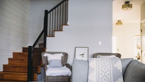 A living room with a sofa, a chair, a staircase, and a framed picture on the wall. - The Lakehouse (Lloydminster)