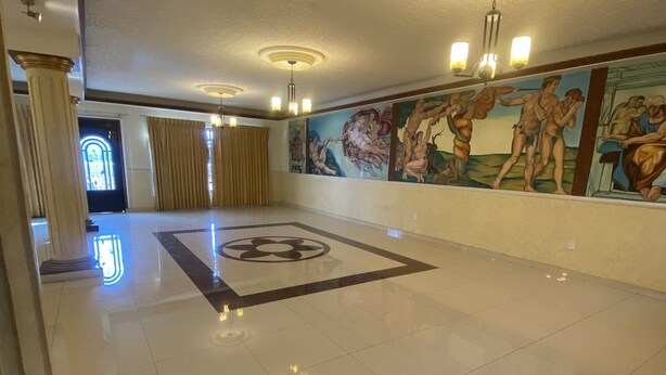 A spacious lobby with a polished floor, a large mural, and classical columns. - AERO-GDL RESIDENCE (Las Pintitas)