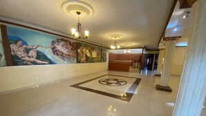 A spacious lobby with a marble floor, a large mural on the wall, and a reception desk. - AERO-GDL RESIDENCE (Las Pintitas)