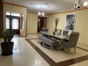 Enjoy meals in this elegant dining area with a large table, tufted chairs, and a beautiful centerpiece.