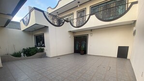 A spacious courtyard with patterned tiles, a black door, and a potted plant. - AERO-GDL RESIDENCE (Las Pintitas)