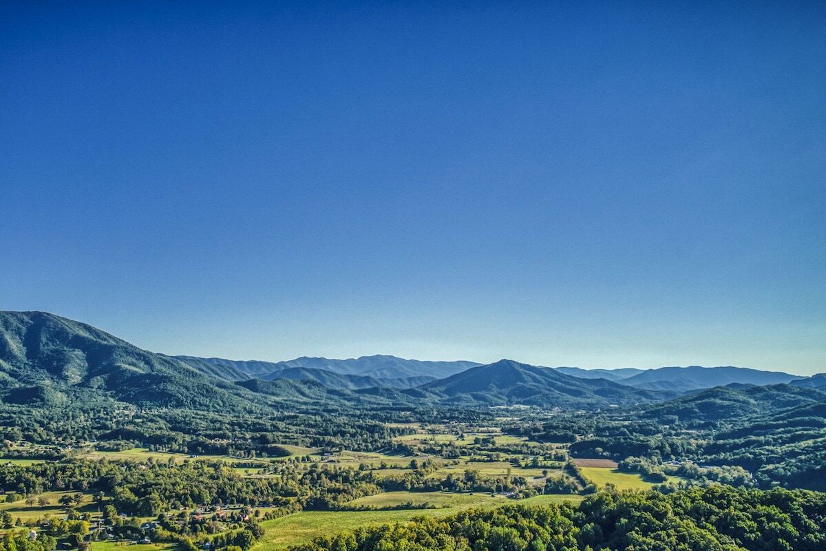 Panoramica su un paesaggio montuoso con dolci colline e edifici sparsi.