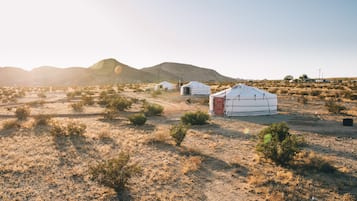 A yurt in a desert landscape with mountains in the background.