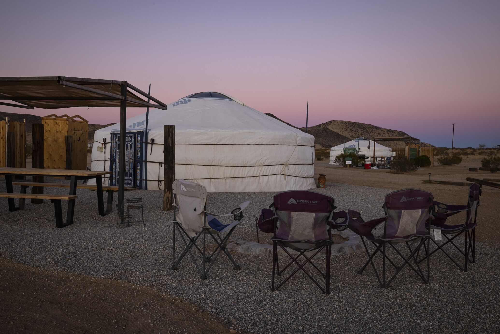 A yurt with a covered seating area and camping chairs.