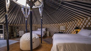 A yurt with two beds, a round seating area, and a wooden floor. - 28 Palms Ranch (Twentynine Palms)